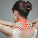 Frau fasst sich an schmerzenden Nacken und Schulter - typische Symptome von Fibromyalgie mit chronischen Muskelschmerzen