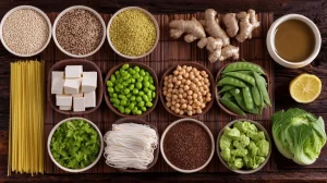 Makrobiotische Ernährung Zutaten von oben: Vollkorngetreide, Quinoa, Tofu, Edamame, grünes Gemüse, Nudeln auf Holztisch mit Bambusmatte