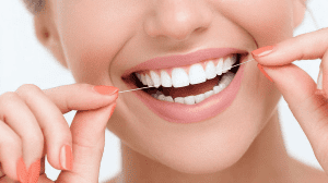 Frau verwendet Zahnseide zwischen weißen Zähnen - Richtige Anwendung für optimale Zahnhygiene