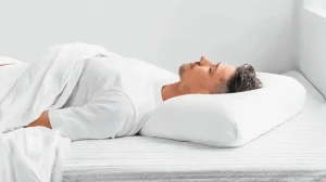 Person in gesunder Rückenlage auf orthopädischem Kissen - die beste Schlafposition für Wirbelsäule und Gehirngesundheit mit korrekter Ausrichtung