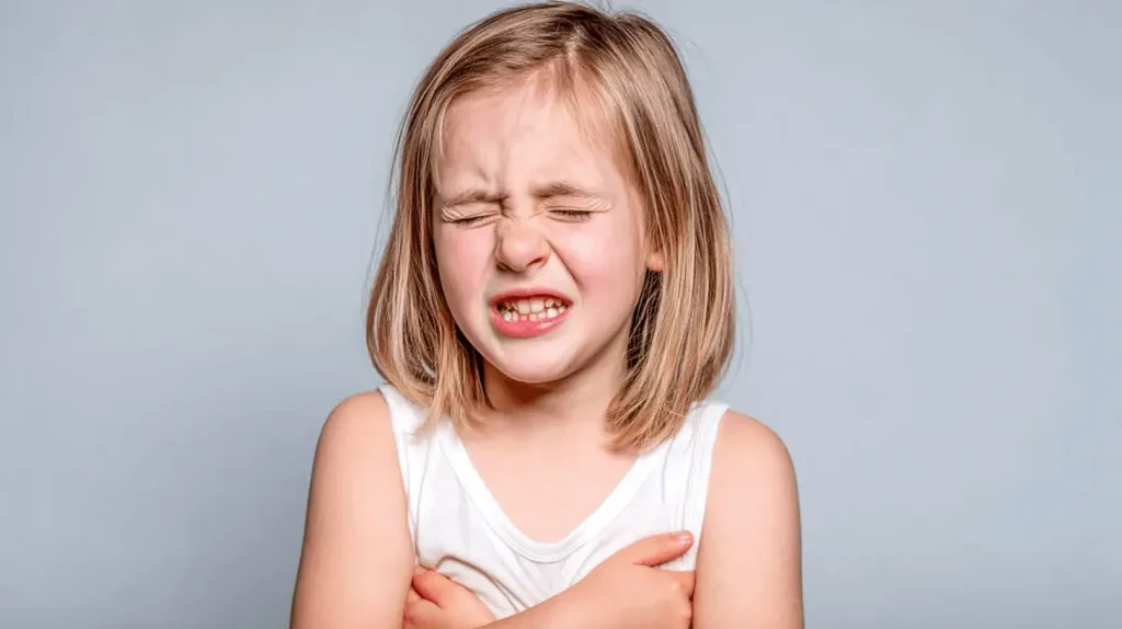 Kind zeigt typische Symptome nach Einatmen von Putzmitteln: Schmerzen, Atembeschwerden und sichtbares Unwohlsein durch chemische Dämpfe