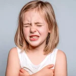 Kind zeigt typische Symptome nach Einatmen von Putzmitteln: Schmerzen, Atembeschwerden und sichtbares Unwohlsein durch chemische Dämpfe