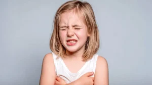 Kind zeigt typische Symptome nach Einatmen von Putzmitteln: Schmerzen, Atembeschwerden und sichtbares Unwohlsein durch chemische Dämpfe