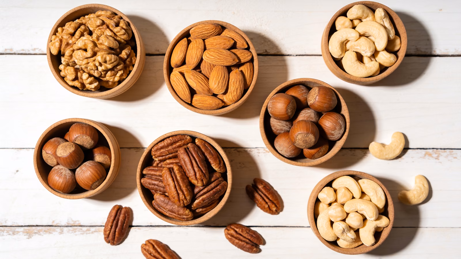 Verschiedene gesunde Nüsse wie Walnüsse, Mandeln, Haselnüsse und Cashews in Holzschalen