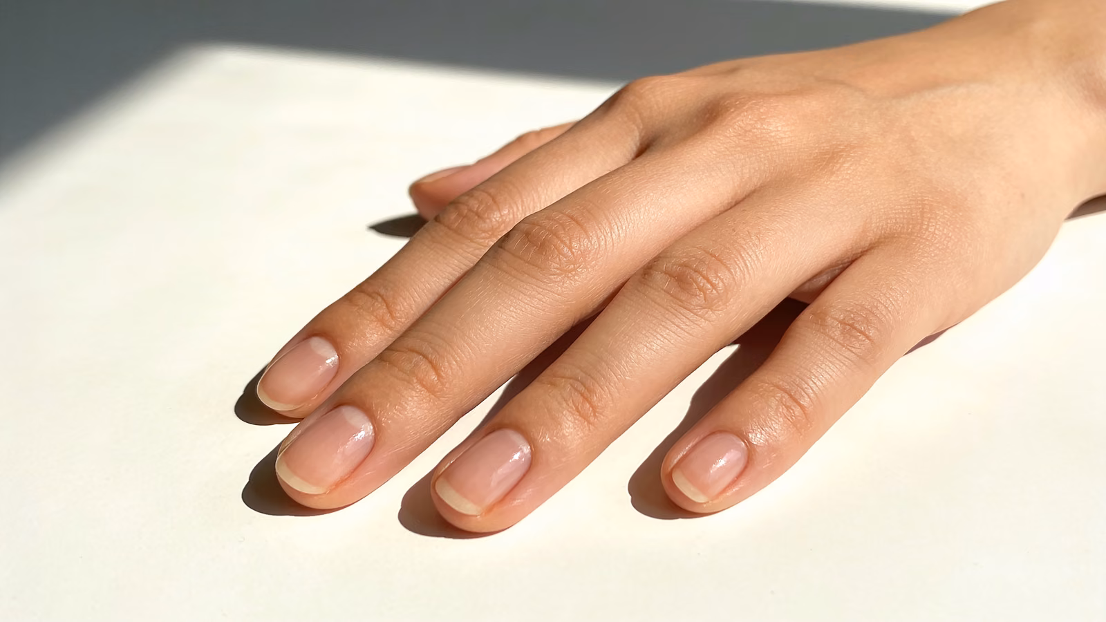 Gepflegte, gesunde Fingernägel einer Hand auf hellem, neutralem Untergrund