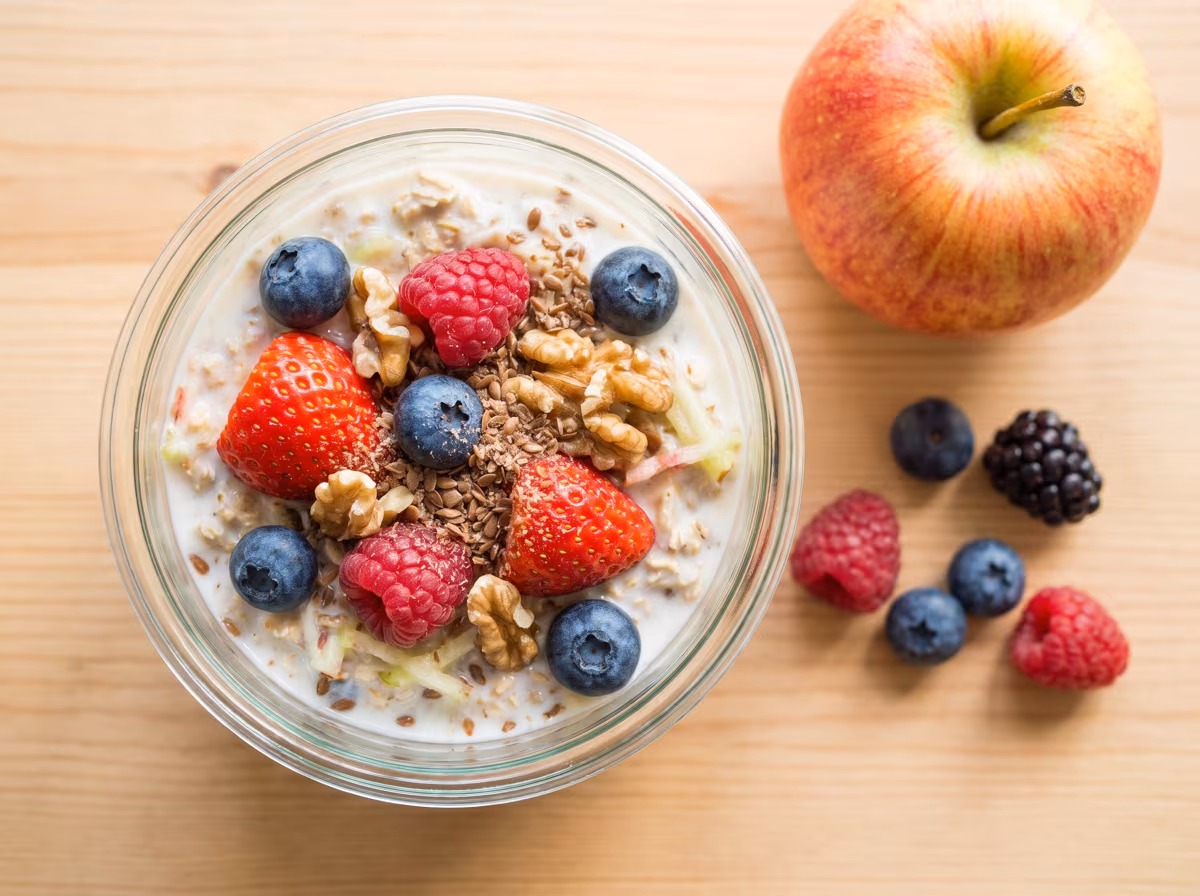 Beeren-Bircher-Müsli im Glas mit Haferflocken, Apfel, frischen Beeren und Walnüssen