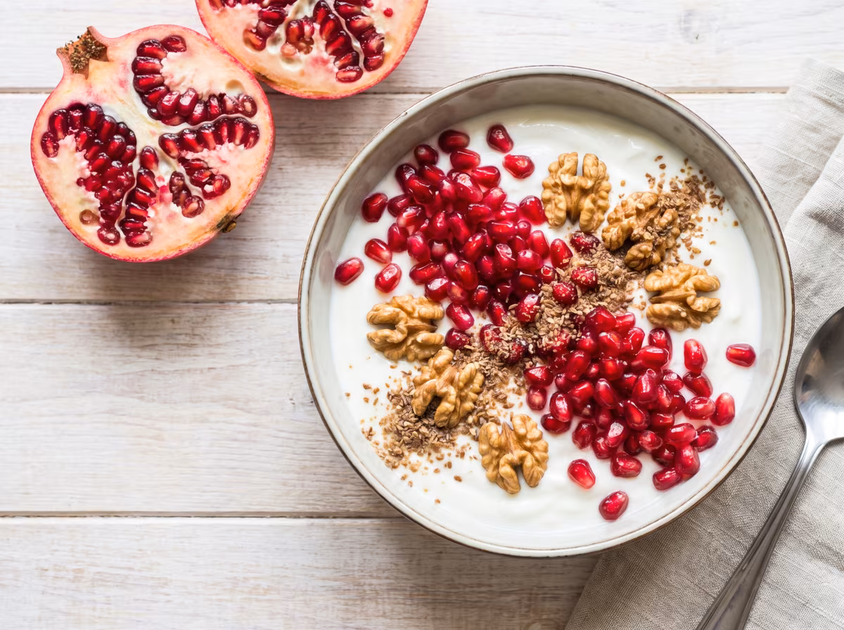 Granatapfel-Bowl mit Naturjoghurt, glänzenden Granatapfelkernen, Walnüssen und Leinsamen
