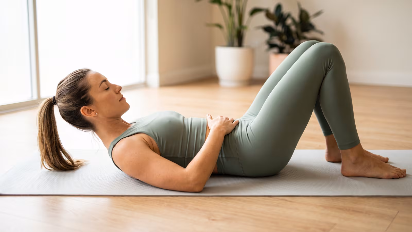 Frau führt die Übung Core-Training auf einer Pilatesmatte im hellen Studio aus